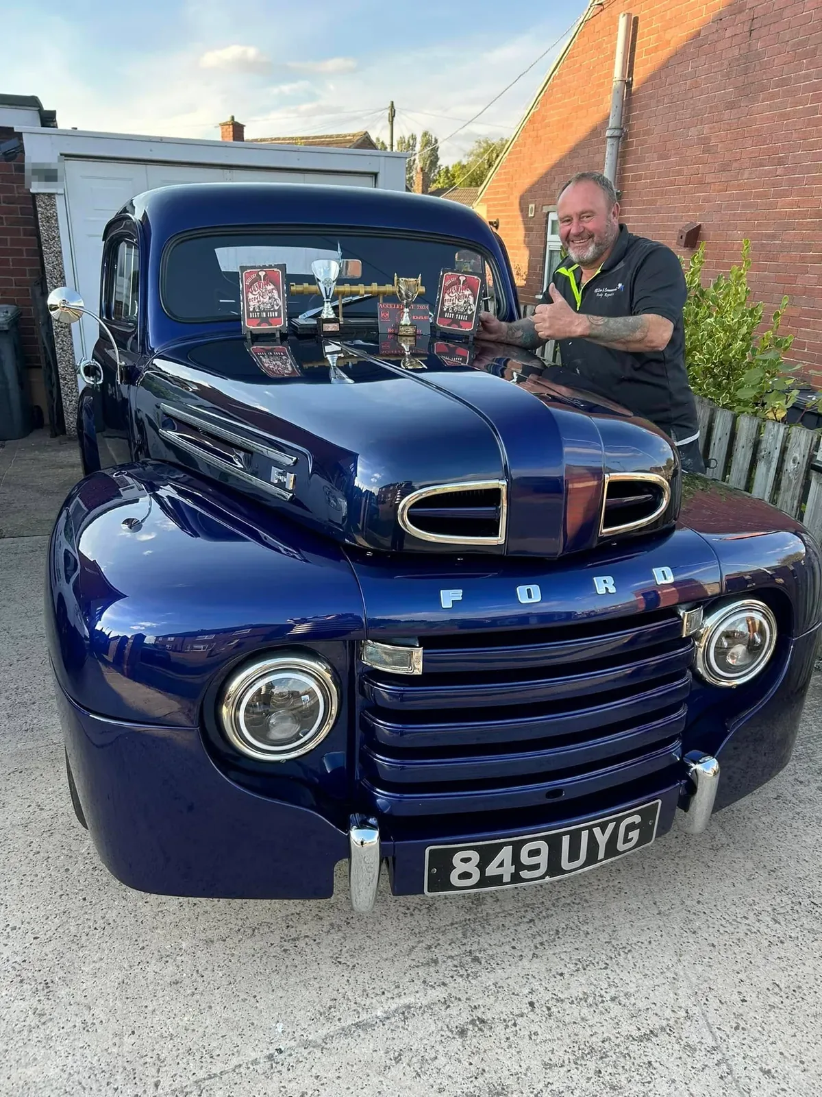 Best in Show and Best Truck plaques and trophies lined up on the bonnet of the blue Ford F100
