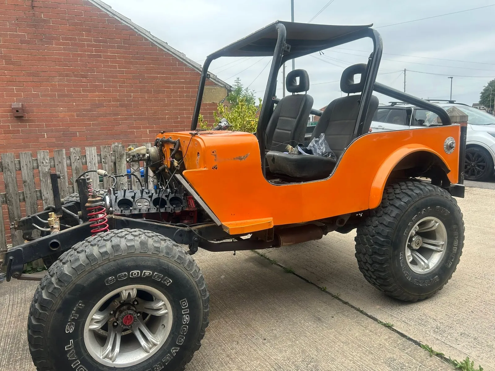 An orange Jeep with its front end stripped down to the engine and chassis