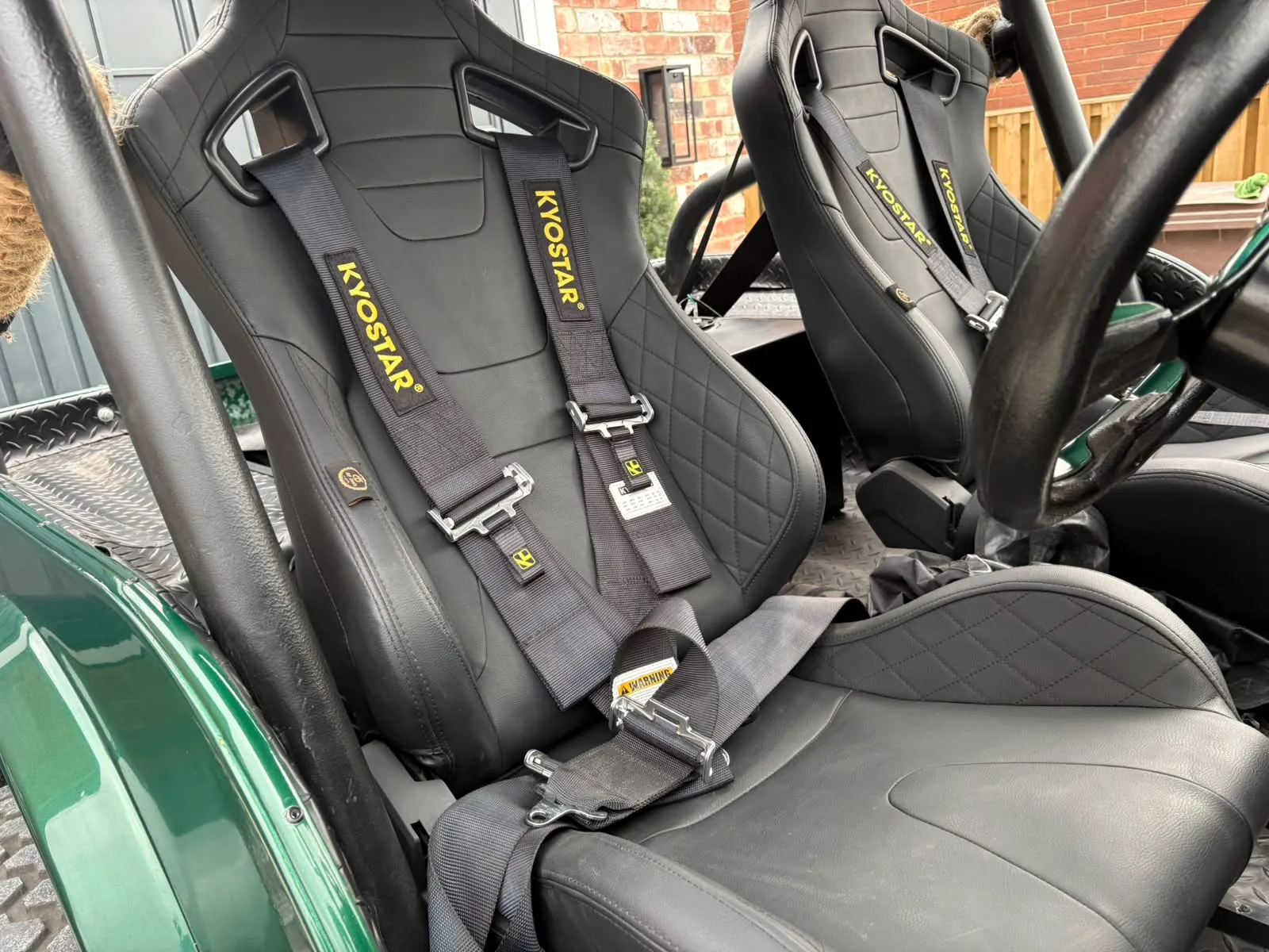 Two black bucket seats with harnesses inside the finished Jeep