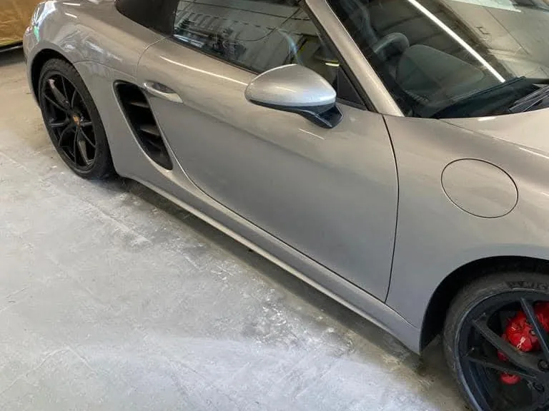 The same side of the Porsche in the workshop, the door and front wing smooth and unmarked